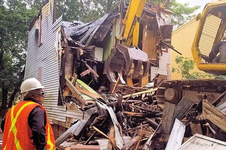 Demolition Work in New Jersey - Crane taking down a house with a worker inspecting.