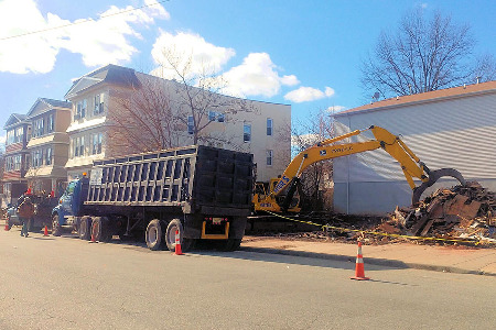 Demolition clean up work in New Jersey - Crane filling truck with old demolished building waste. 